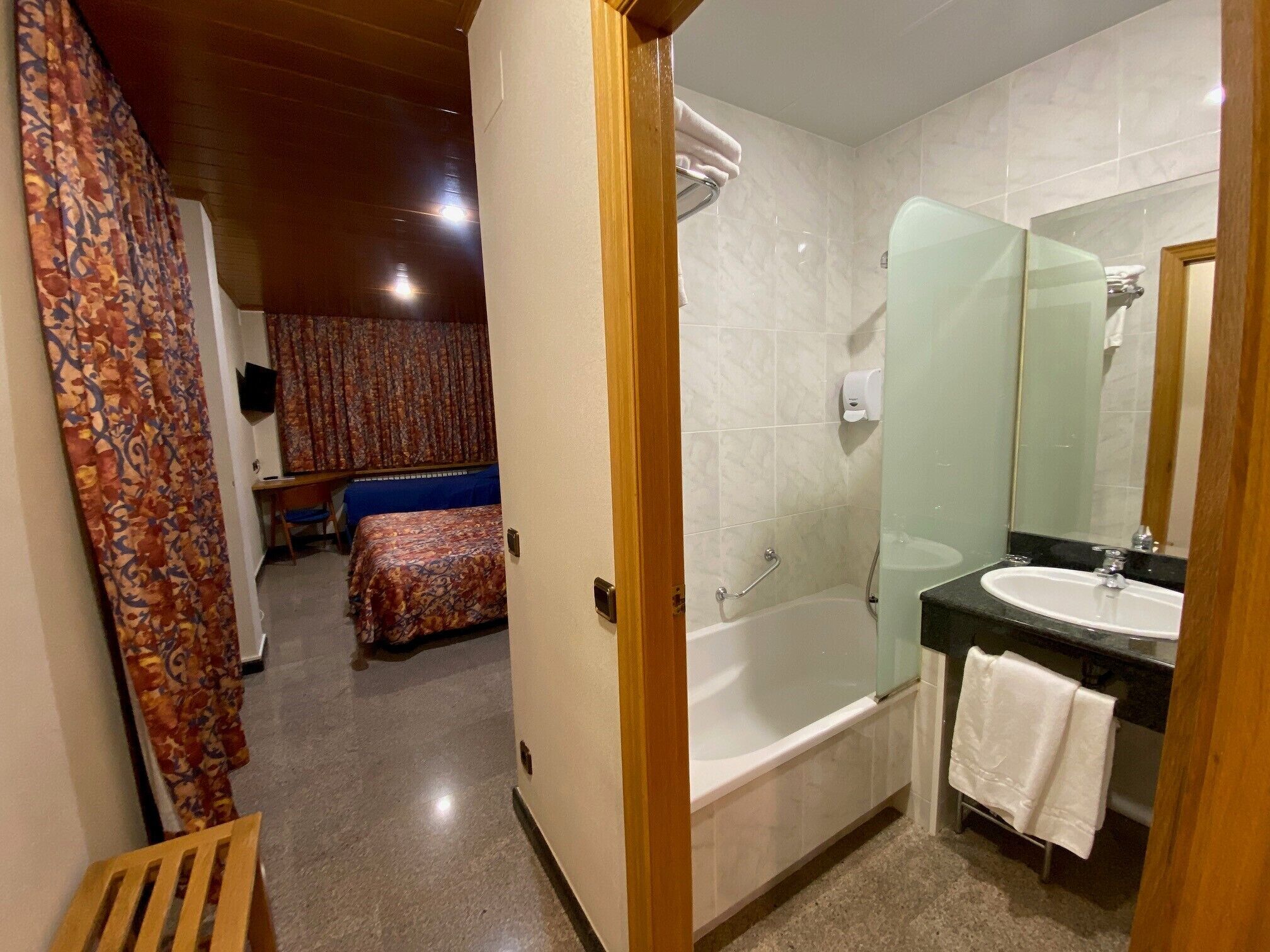 Een hotelkamer met een bed, een badkamer met een bad, een wastafel en een spiegel.