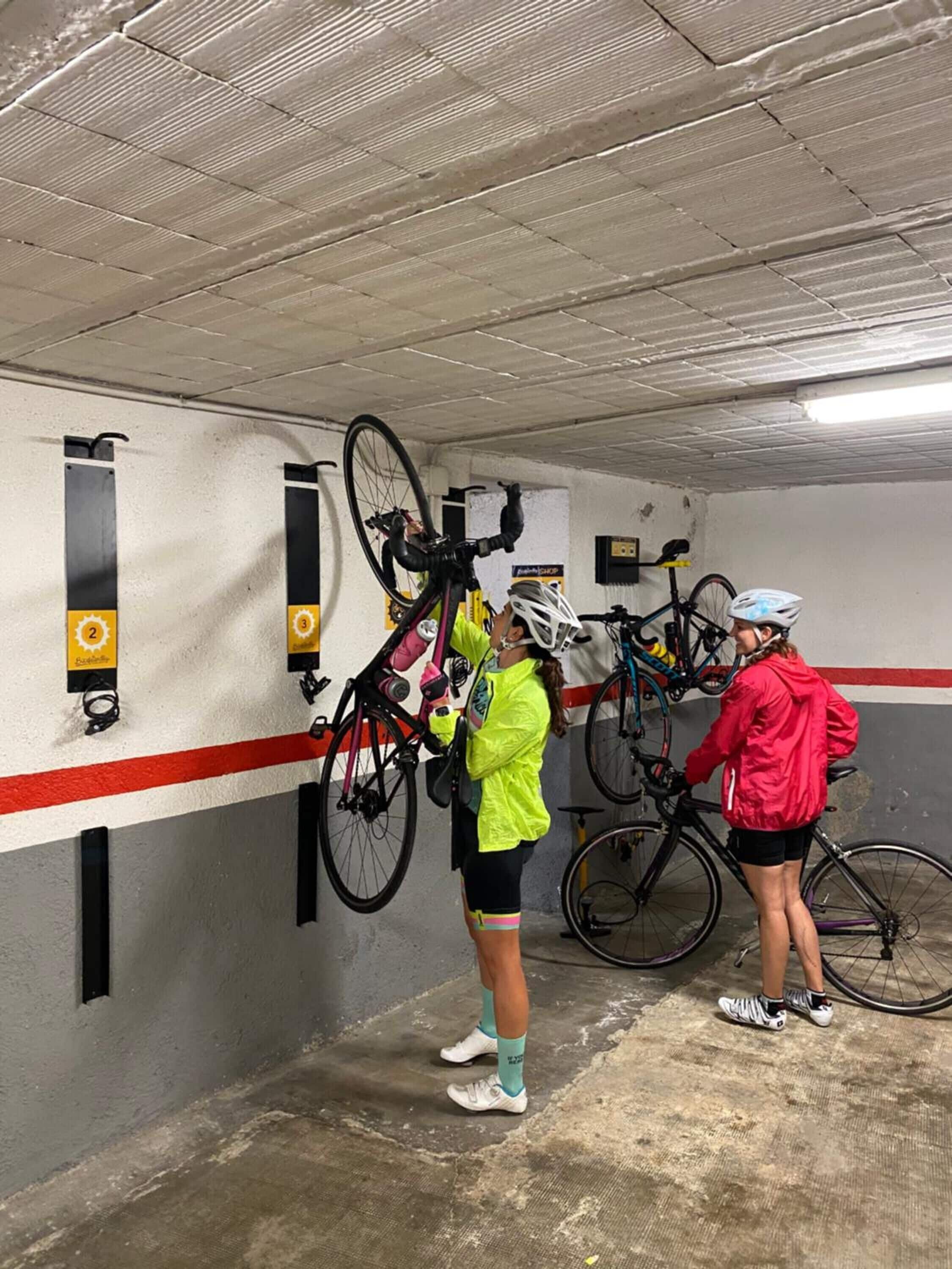 Un aparcamiento con bicicletas estacionadas contra las paredes.