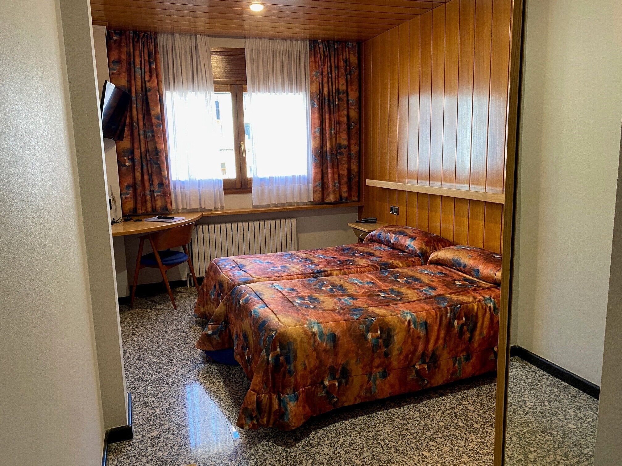 A bedroom with a bed, a desk, and a chair.