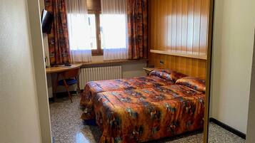 A bedroom with a bed, a desk, and a chair.