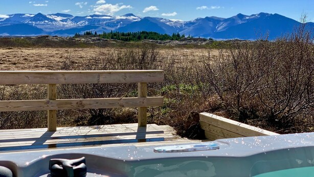A hot tub with a wooden deck and a view of mountains.