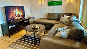 A modern living room with a sectional sofa, a television, a coffee table, and two wall-mounted lamps.