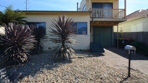 A two-story house with a balcony, a garage, and a gravel driveway. - Seahaven Beach House - This brilliant beach house sleeps up to 8 adults and 2 children. (shellharbour)