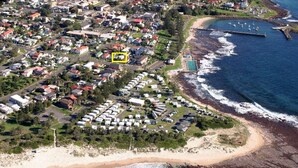 An aerial view of a coastal residential area with a beach, a marina, and a row of mobile homes. - Seahaven Beach House - This brilliant beach house sleeps up to 8 adults and 2 children. (shellharbour)