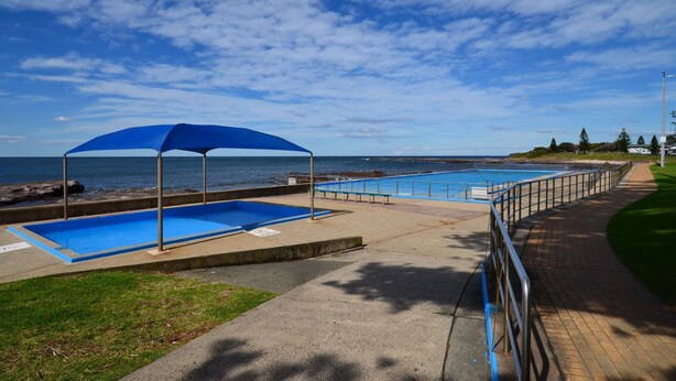 A pool area with two pools, a blue umbrella, and a view of the ocean. - Seahaven Beach House - This brilliant beach house sleeps up to 8 adults and 2 children. (shellharbour)