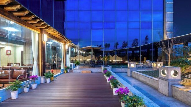 An outdoor area with a wooden deck, potted plants, and outdoor seating. - Heping Hotel (Tongxiang)