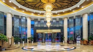A lobby with a central chandelier, large columns, and a patterned floor. - Heping Hotel (Tongxiang)