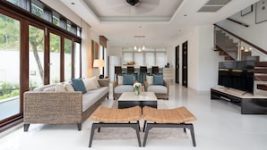 A spacious living room with a sofa, coffee table, and TV. - Gardenia Pool Villa - 2 Bedroom (Ko Samui)