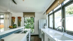 A modern kitchen with a large island, a refrigerator, and a sink. - Gardenia Pool Villa - 2 Bedroom (Ko Samui)