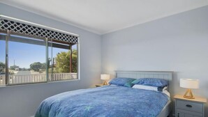 A bedroom with a bed, two bedside tables, a window with a view, and a patterned bedspread. - Serindipity - 180 Degrees ocean view (Yanchep)