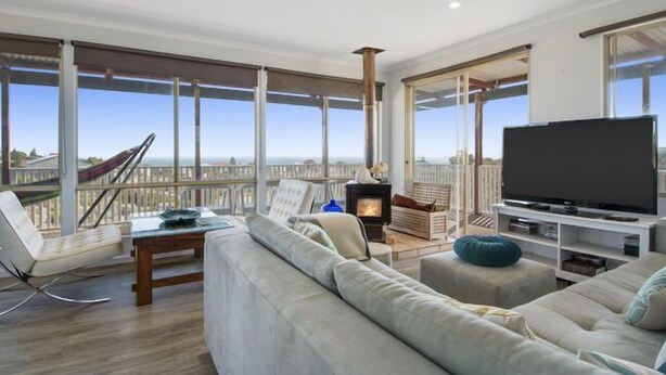 A spacious living room with a large sofa, a television, and a fireplace. - Serindipity - 180 Degrees ocean view (Yanchep)