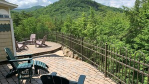 A terrace with outdoor seating and a view of a forested mountain. - Elegant Vacation Home in picturesque Jackson NH perfect for reunions, gatherings (Jackson)