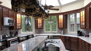 A spacious kitchen with a large island, modern appliances, and large windows offering views of the outdoors. - Elegant Vacation Home in picturesque Jackson NH perfect for reunions, gatherings (Jackson)