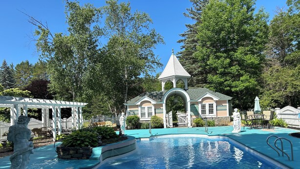 A swimming pool with a gazebo, a statue, and a building with a tower in the background. - Elegant Vacation Home in picturesque Jackson NH perfect for reunions, gatherings (Jackson)