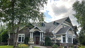 A large, two-story house with a stone facade, a prominent front porch, and a well-maintained lawn. - Elegant Vacation Home in picturesque Jackson NH perfect for reunions, gatherings (Jackson)