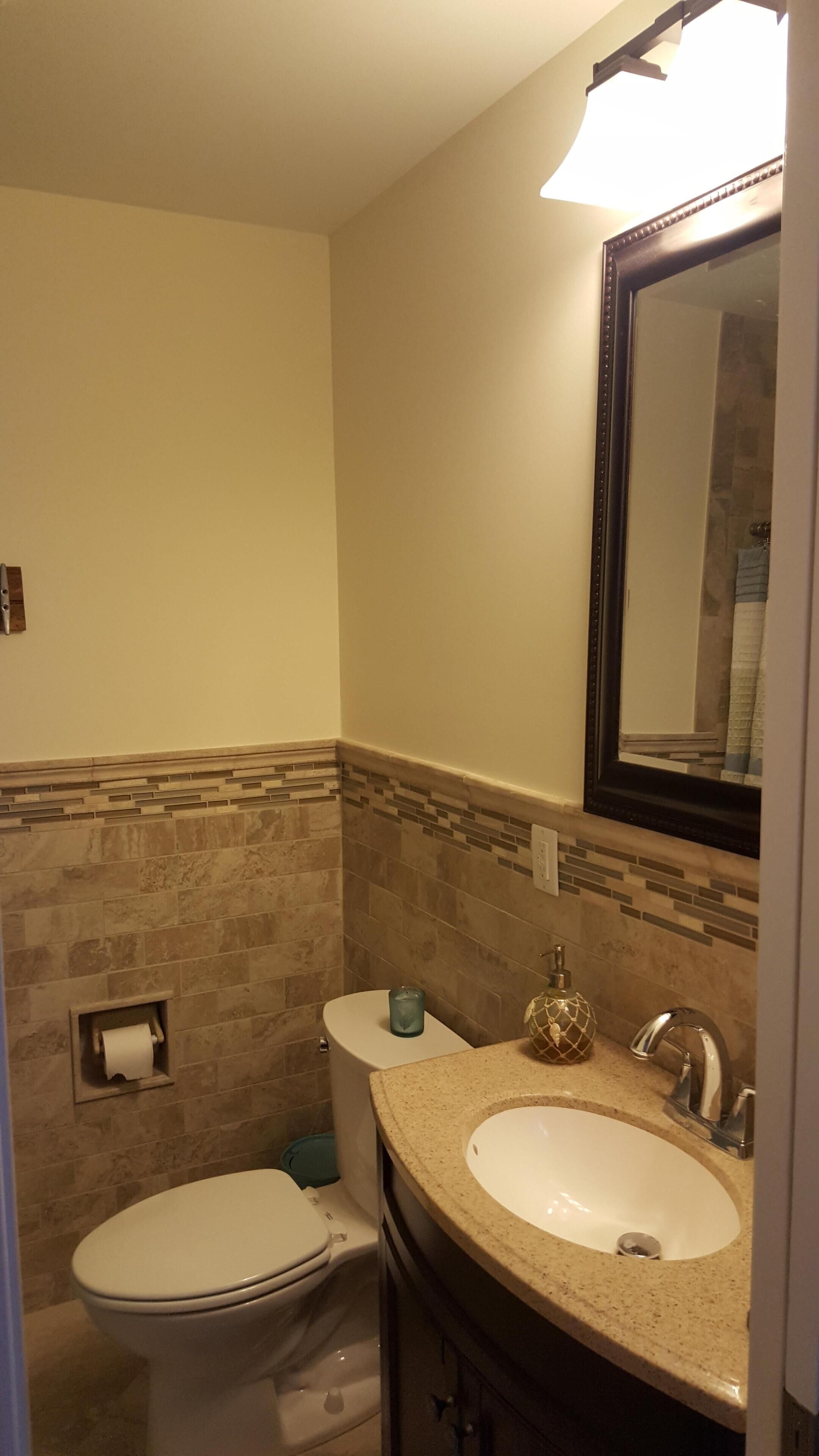Une salle de bain avec des toilettes, un lavabo et un miroir.
