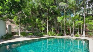 A clear blue swimming pool surrounded by lush greenery and trees. - Surfside 6 at James Cook - Clarkes Beach (Byron Shire)