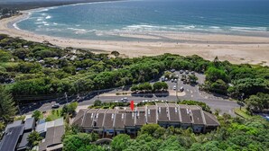 A coastal hotel with a parking lot, beachfront view, and a building with a sign reading "SURFSIDE 6 @ JAMES COOK". - Surfside 6 at James Cook - Clarkes Beach (Byron Shire)
