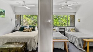 A modern bedroom with two beds, a wooden bench, and a suitcase. - Surfside 6 at James Cook - Clarkes Beach (Byron Shire)