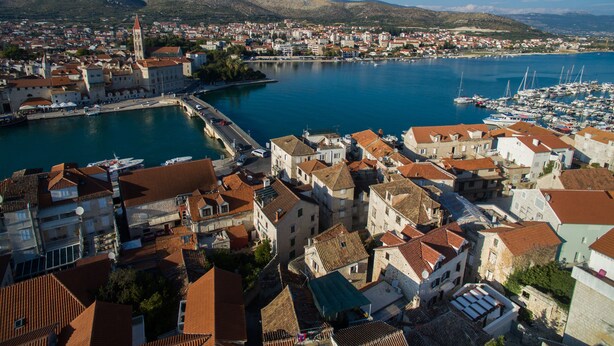 Un pueblo costero con edificios históricos, un puerto deportivo y un puente.