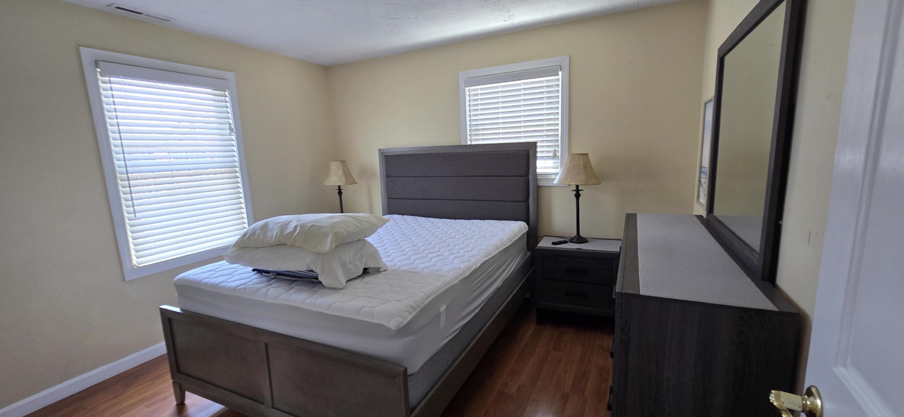 Une chambre à coucher comprenant un lit, des tables de chevet, une commode et un miroir.