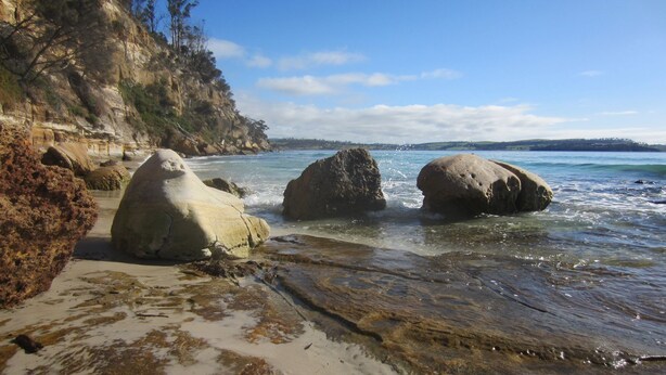 Une plage avec de gros rochers et une eau cristalline.