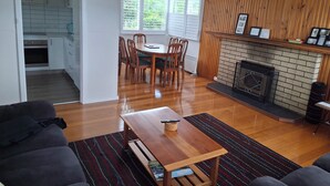 Un salon moderne avec une table à manger en bois, une cheminée et une cuisine en arrière-plan.