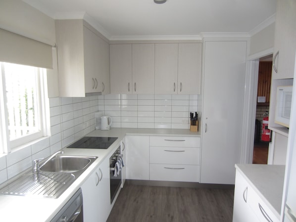 A modern kitchen with white cabinets, a stainless steel sink, and a built-in oven.