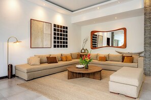 A modern living room with a sectional sofa, a round coffee table, and a large mirror.