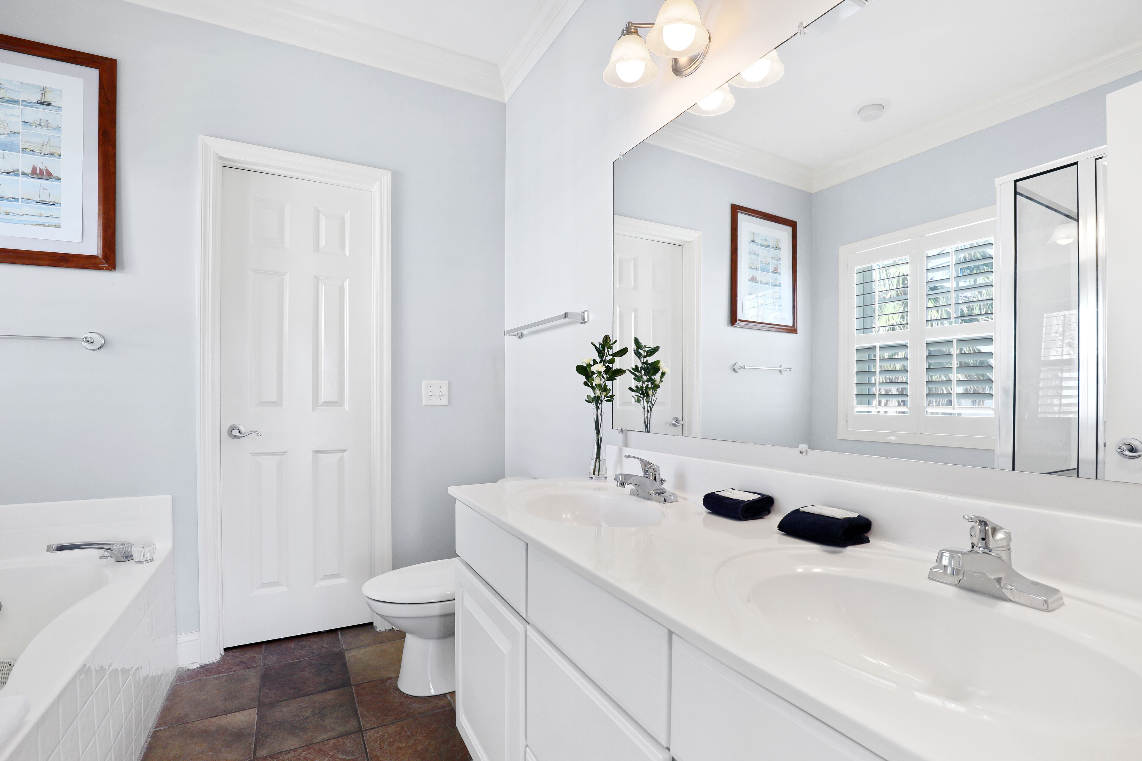 A modern bathroom with a white sink, two basins, a large mirror, and a white toilet.