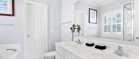 A modern bathroom with a white sink, two basins, a large mirror, and a white toilet.
