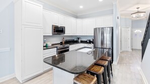 A modern kitchen with white cabinets, stainless steel appliances, and a granite countertop.
