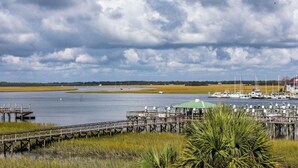 Un port de plaisance avec des bateaux amarrés, une jetée et une zone herbeuse avec un palmier.