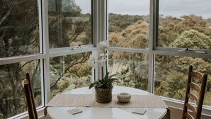 A room with a large window, a table with a woven basket and a small bowl, and a chair. - Cliff Beach House, luxury Yallingup accommodation in secluded private estate (Yallingup)