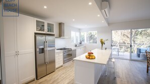 A modern kitchen with white cabinetry, stainless steel appliances, and a wooden floor. - Cliff Beach House, luxury Yallingup accommodation in secluded private estate (Yallingup)