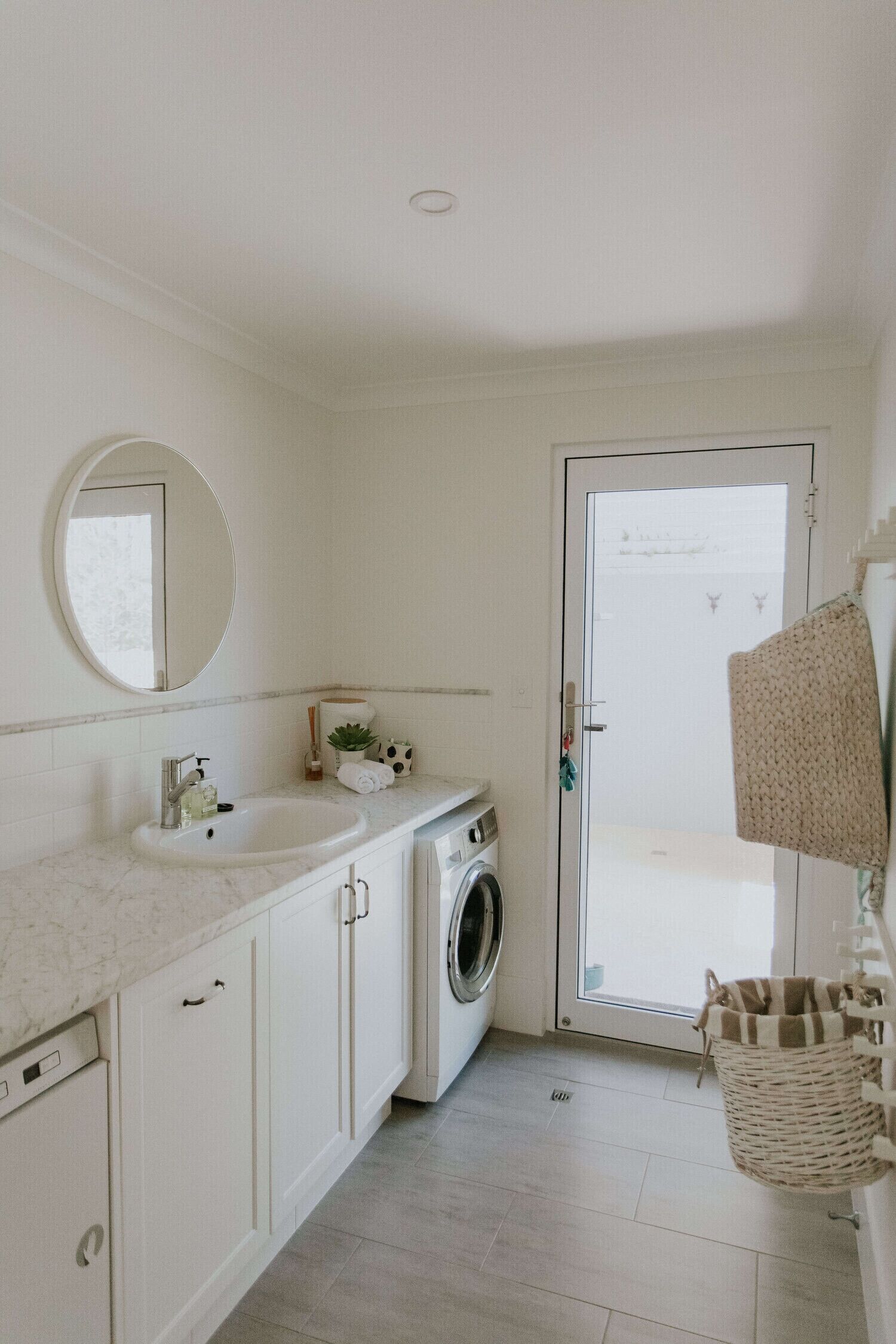 A bathroom with a sink, mirror, and a washing machine.