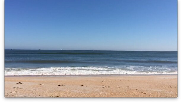 Una playa con cielo despejado y mar tranquilo.