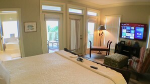 Habitación de hotel con una cama grande, una silla, una mesita, un televisor y un balcón con vistas.