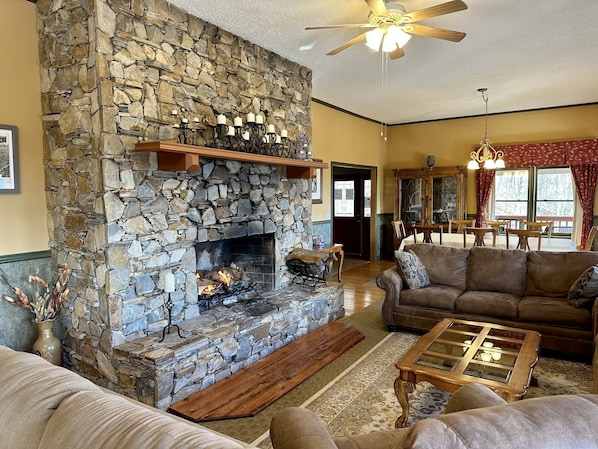 Una sala de estar acogedora con chimenea de piedra, sofás de cuero y una mesa de centro de madera.