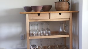 Une console en bois ornée de bols, d’un panier et de verres à vin.