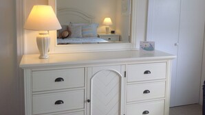 Une commode blanche avec des tiroirs et un miroir au-dessus.
