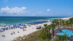 A beach resort with a swimming pool, beach umbrellas, and palm trees. - Corner 1st Floor, largest two bdrm with Bunk Room and Huge balcony, New Furn. (Panama City Beach)