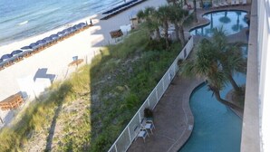 A resort with a beach, a pool, and a fenced area with lounge chairs. - Corner 1st Floor, largest two bdrm with Bunk Room and Huge balcony, New Furn. (Panama City Beach)