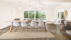 A dining area with a wooden table, four chairs, and pendant lights.