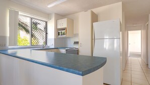 A modern kitchen with a large island, white cabinetry, and a built-in oven.