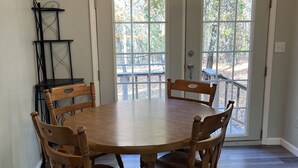Un comedor con una mesa y sillas de madera, una araña y vistas amplias por las ventanas.