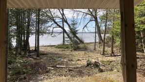 Un espacio al aire libre techado con vista a un lago y árboles circundantes.