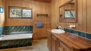 A wooden-paneled bathroom with a bathtub, sink, and mirror.