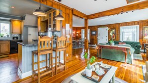 A spacious kitchen with wooden cabinets, a dining area with a green sofa, and a wooden dining table.