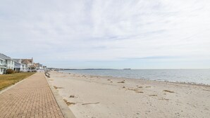 A beach with a paved walkway, houses along the shore, and a distant pier. - Laurel Beach-Milford (Milford)